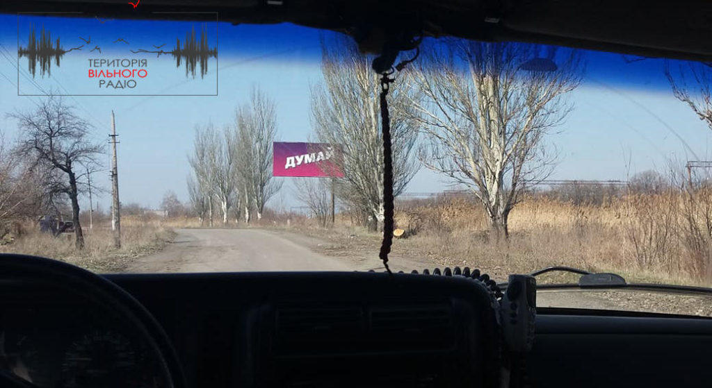 Фотофакт: В сірій зоні в районі смт Зайцеве висить плакат “Думай”, а на КПВВ – реклама Порошенка