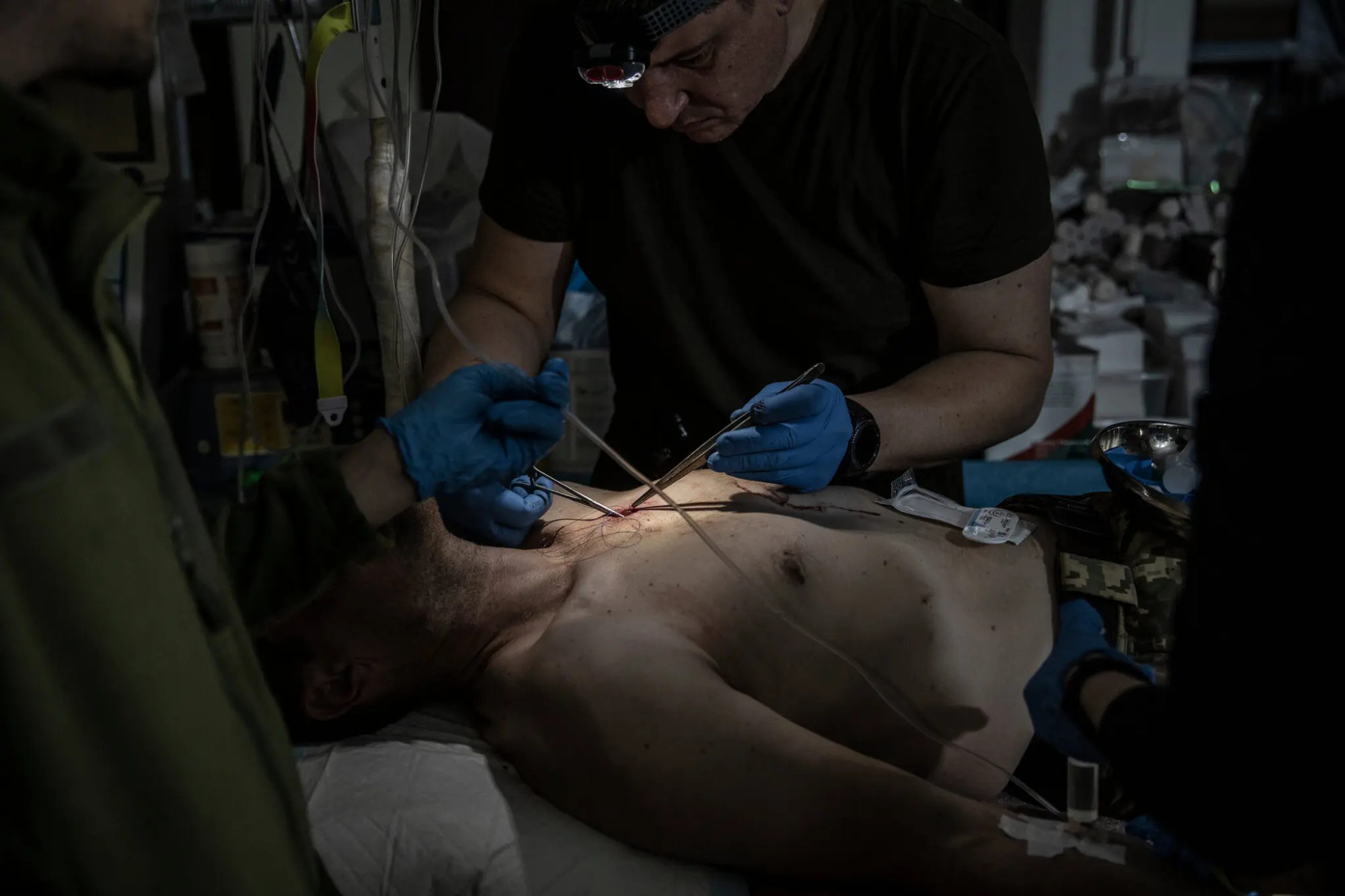 лікар зашиває рану пораненому військовому в лікарні в Бахмуті