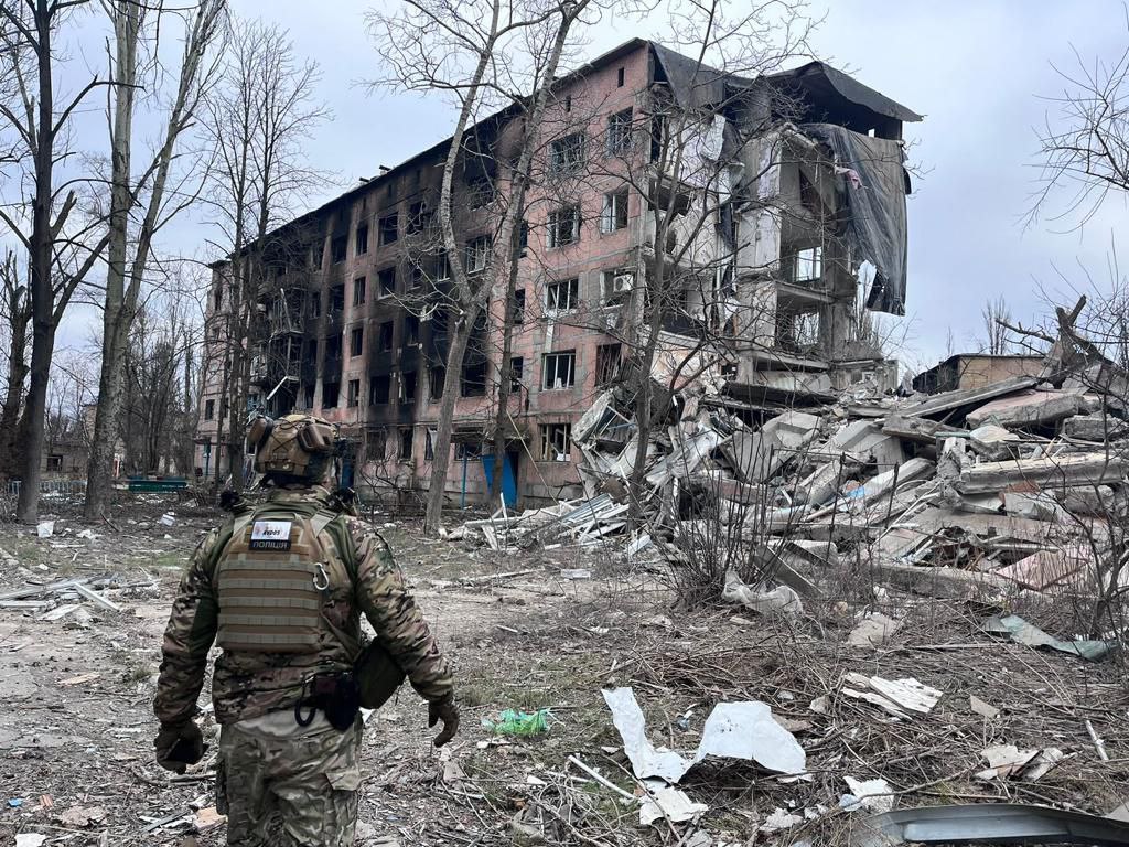 Поліцейський оглядає руїни багатоквартирного будинку, знищеного російськими окупантами в Авдіївці