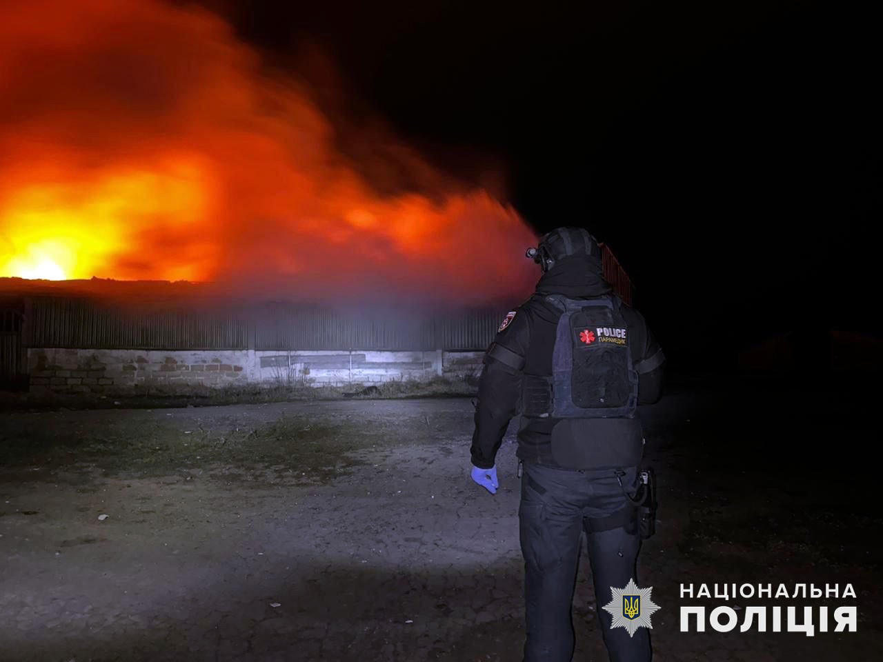 Поліцейський на Донеччині спостерігає за спричиненою обстрілом пожежою