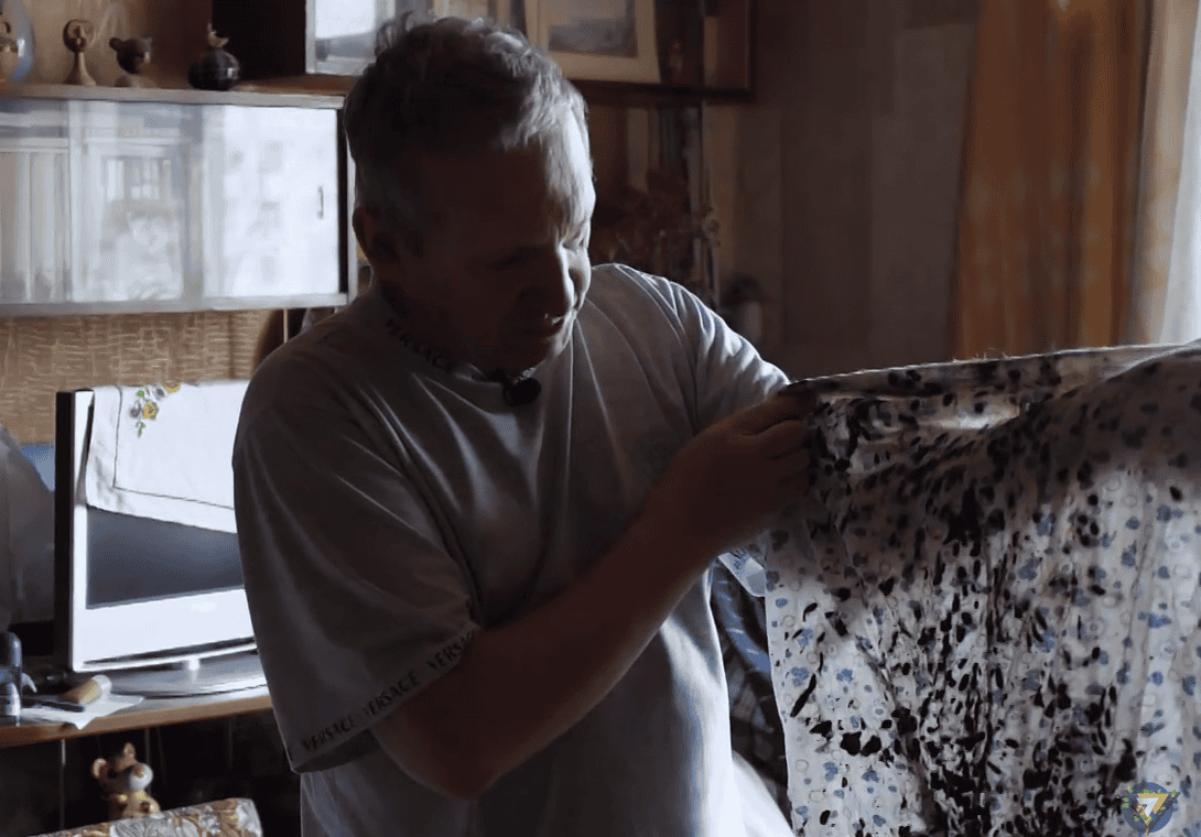 В’ячеслав Долженко показує нічну сорочку, у якій витягнув матір з пожежі. Скриншот Вільного Радіо з відео ТВ-7 Маріуполь